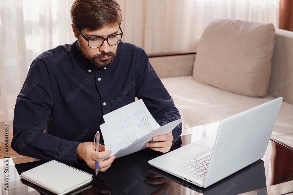 Entrepreneur works with a laptop and keeps a document in a home office Entrepreneur works with a laptop and keeps a document in a home office