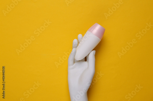 antiperspirant in mannequin hand on yellow background