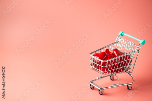 Shopping cart full of hearts for Valentine's Day on pink background