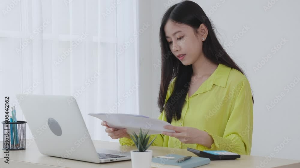 Young asian business woman working on laptop computer and looking graph and chart of report for profit on paper at home office, businesswoman looking investment and income, data of infographic. Young asian business woman working on laptop computer and looking graph and chart of report for profit on paper at home office, businesswoman looking investment and income, data of infographic.