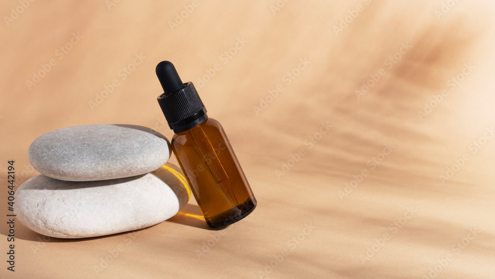 Cosmetics oil or essence in glass bottle with shadows on beige background. Banner. Close up.