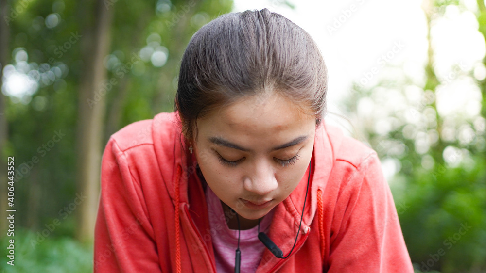 Asian women rest after running. wearing jacket and earphone Asian women rest after running. wearing jacket and earphone