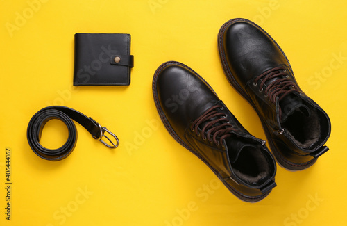 Men's accessories on a yellow background. Leather boots, wallet and belt. Top view. Flat lay