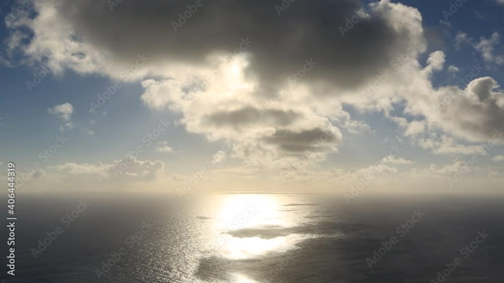 Clouds are passing by the sky and sun turns into the ocean. Calming atmosphere.