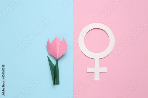 Hand made origami tulip flower and venus symbol on pink blue background. Womens day concept