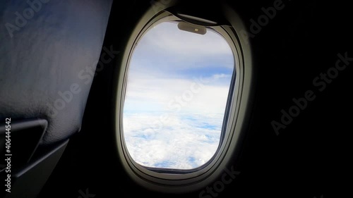 sky view with white clouds from window of passenger seat in cabin on commercial airplane. Transportation and travel concept.