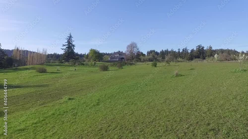 Aerial drone shot flying over female runner on trail in green meadow on a clear sky day Aerial drone shot flying over female runner on trail in green meadow on a clear sky day
