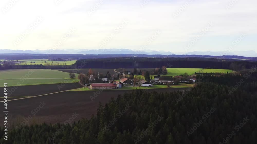 Timelapse of a idyllic village behind a forest in front of the alp mountains in the background Timelapse of a idyllic village behind a forest in front of the alp mountains in the background