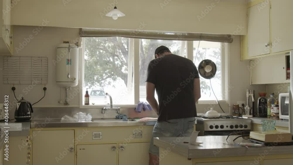 Wide shot of man in bach kitchen preparing salmon fillets for curing. Wide shot of man in bach kitchen preparing salmon fillets for curing.