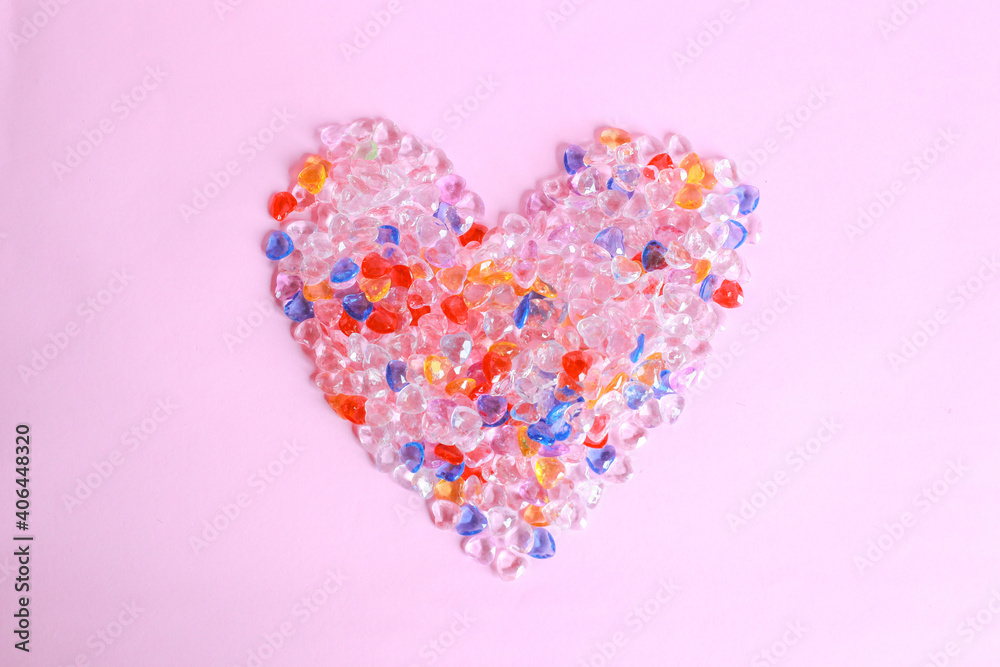 Colorful heart shape from marbles on pink background