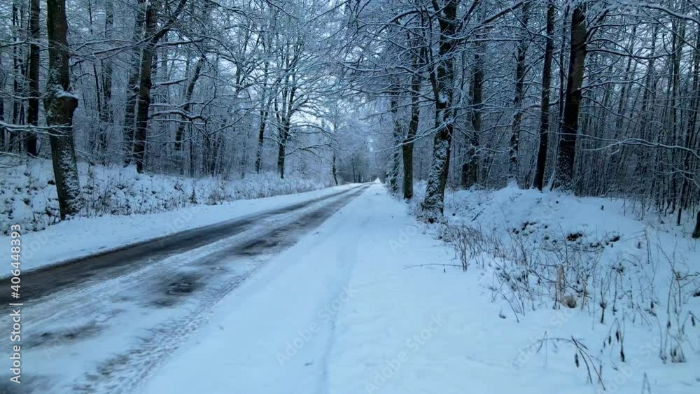 Low angle drone flying along the snow-covered and ice-covered countryside forest road, huge snowdrifts on sides Low angle drone flying along the snow-covered and ice-covered countryside forest road, huge snowdrifts on sides
