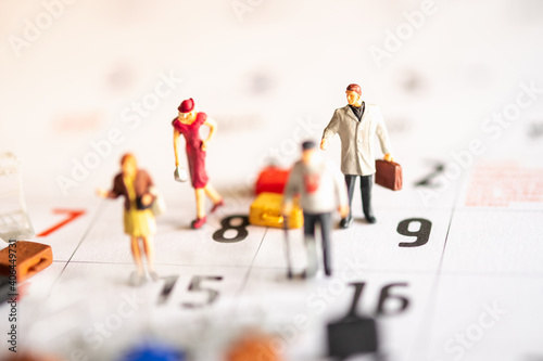 Miniature Tourists standing on the calendar with bags
