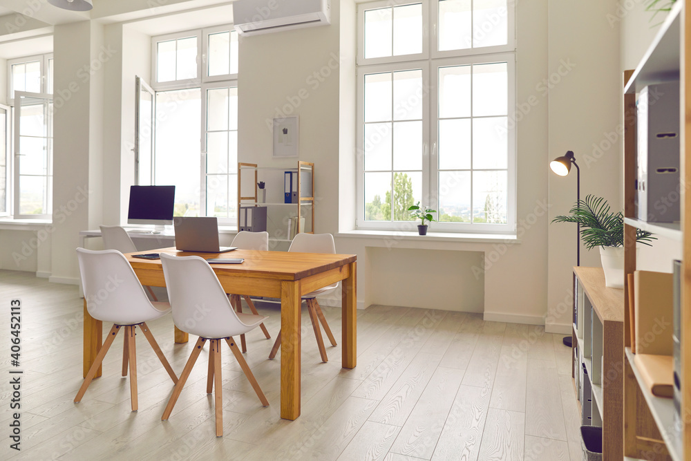 Side view of the workplace with a wooden table and chairs in the middle of the room. Side view of the workplace with a wooden table and chairs in the middle of the room.