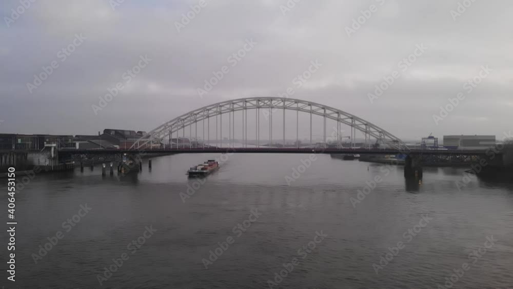 Container ship passing under bridge at the River Noord in Netherland. Aerial. Slowmo. Container ship passing under bridge at the River Noord in Netherland. Aerial. Slowmo.