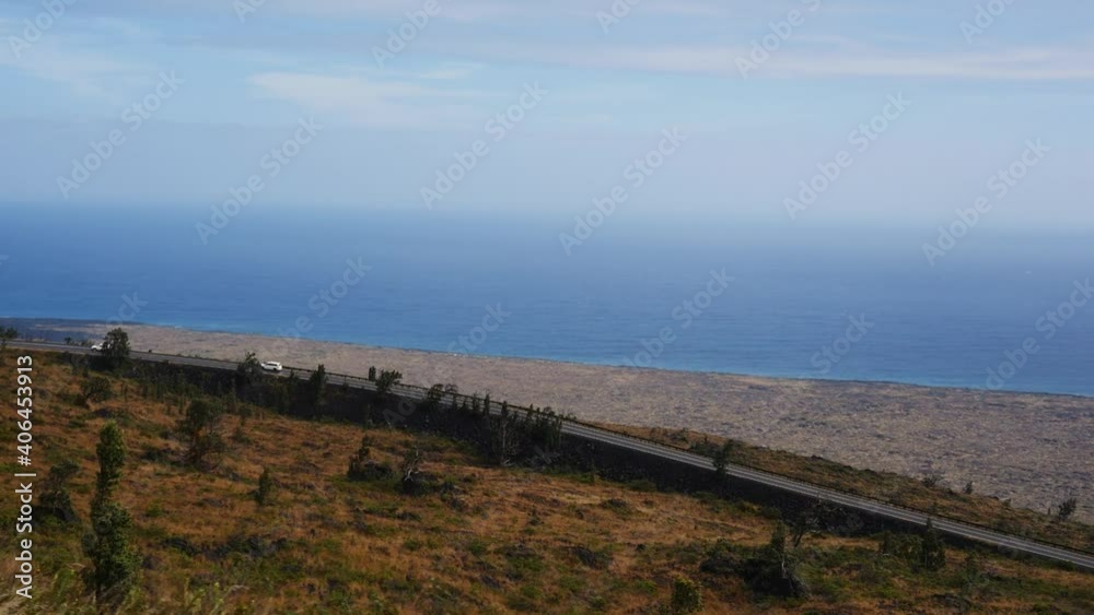 Driving down the side of Mauna Kea volcano in Hawaii looking out to the vast Pacific Ocean with the winding road and lava flows below. Driving down the side of Mauna Kea volcano in Hawaii looking out to the vast Pacific Ocean with the winding road and lava flows below.