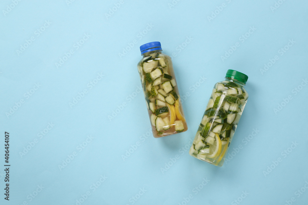 Detox drink, cucumber lemonade bottles on blue background. Top view. Detox drink, cucumber lemonade bottles on blue background. Top view.