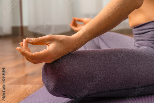 Young woman meditating in the lotus pose at home. Practicing yoga indoors. Harmony, yoga practice, balance, meditation, relaxation at home, healthy lifestyle concept.