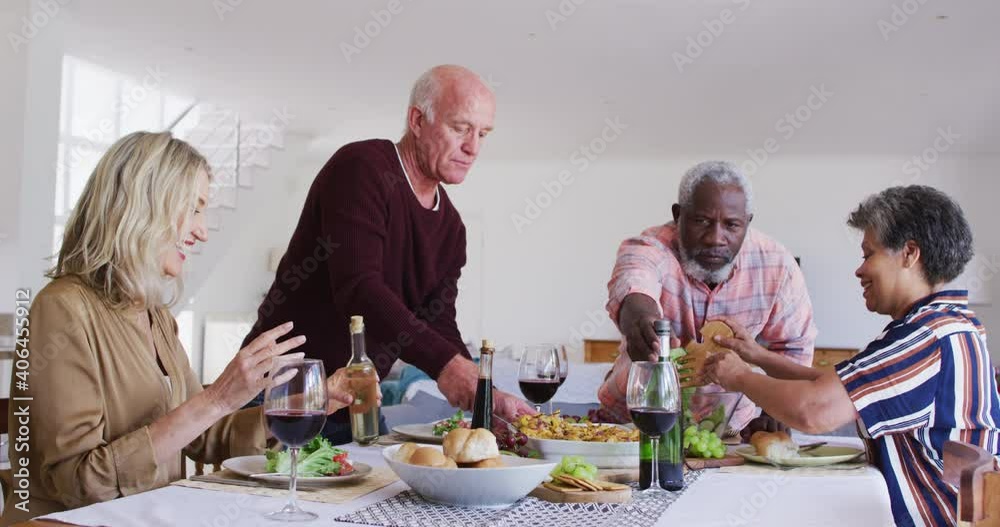 Diverse senior couples sitting by a table drinking wine and eating dinner Diverse senior couples sitting by a table drinking wine and eating dinner