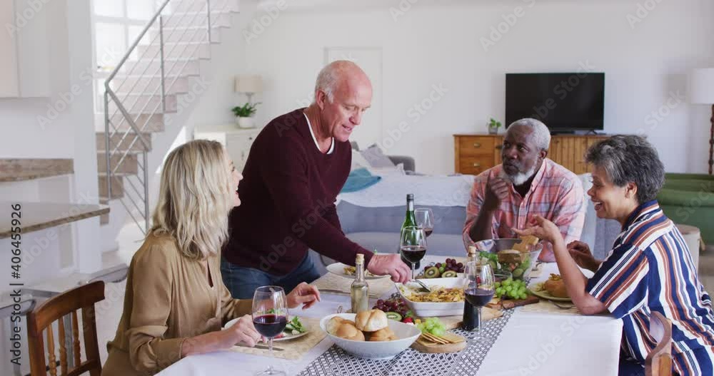 Diverse senior couples sitting by a table drinking wine and eating dinner Diverse senior couples sitting by a table drinking wine and eating dinner