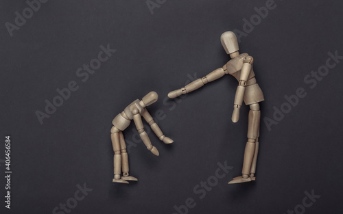 Wooden puppet scolds child puppet on gray background