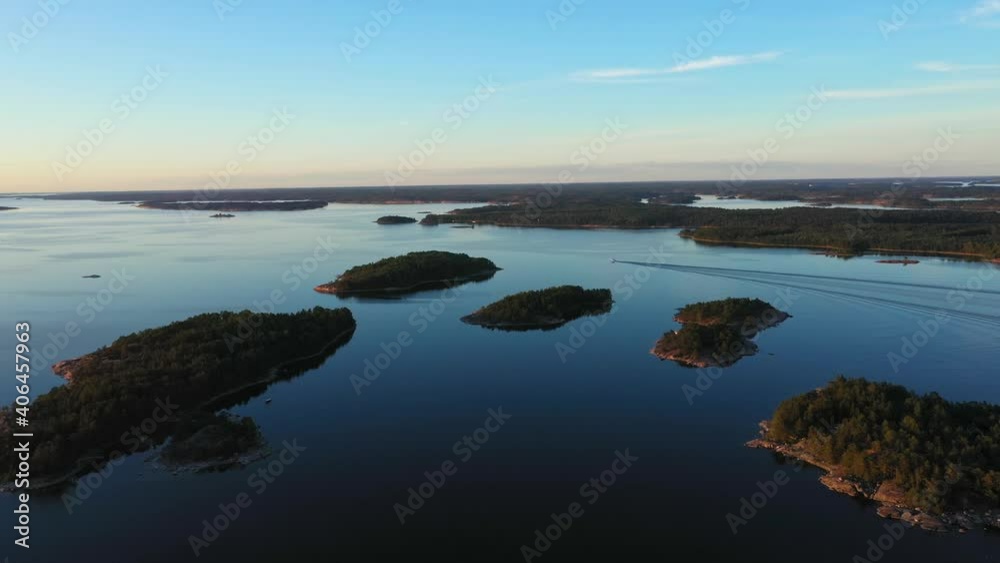 Aerial view of a motorboat surrounded by islands, in calm waters of the Baltic sea, serene, summer sunset, in Scandinavia - dolly, drone shot Aerial view of a motorboat surrounded by islands, in calm waters of the Baltic sea, serene, summer sunset, in Scandinavia - dolly, drone shot