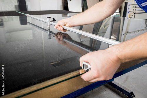 The glazier cuts the glass with a cutting sledge on a professional table in the workplace