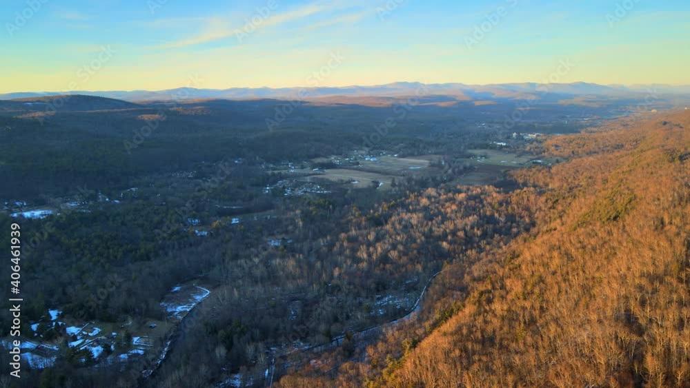 Flying high above a vast valley at sunset, with distant mountains and farmlands and forest during winter. Flying high above a vast valley at sunset, with distant mountains and farmlands and forest during winter.
