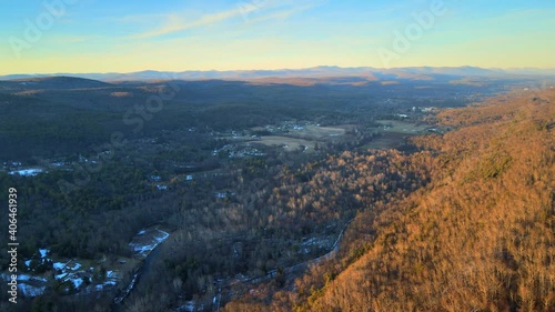 Flying high above a vast valley at sunset, with distant mountains and farmlands and forest during winter. photo