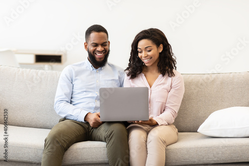 African american couple sitting on couch, using laptop computer
