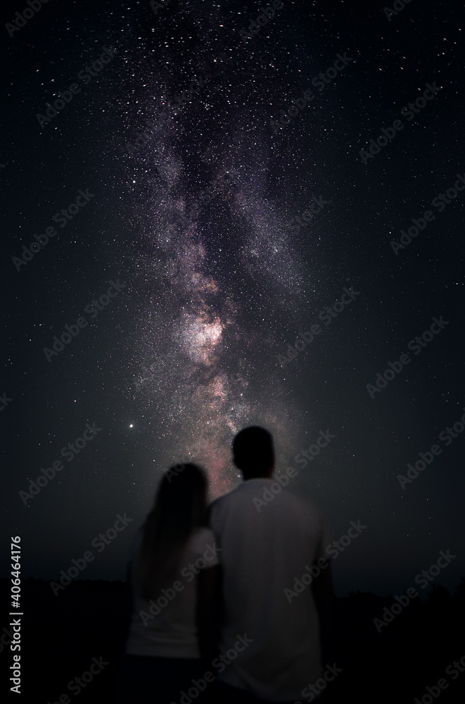 Soft defocused silhouette of man and woman couple are starring on the galaxy milky way