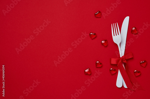 Valentines day background or concept with empty white plate, small heart-shaped plate with small hearts inside and whiteware on scarlet or red background. Banner. Top view with copy space.