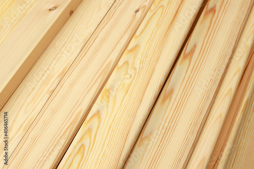 Narrow wooden slats or boards in close-up lie in a stack. This is a noble polished wood in the carpentry shop. Background or screen saver for advertising a range of construction products.