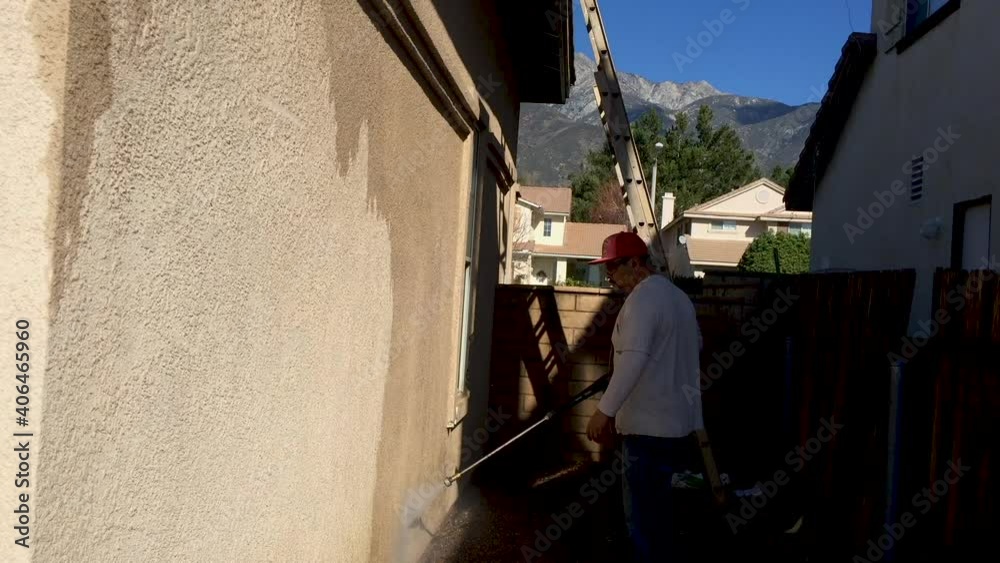 A cleaning service or painter tradesman pressure washing a concrete wall, starting from the bottom and working his way up. A cleaning service or painter tradesman pressure washing a concrete wall, starting from the bottom and working his way up.