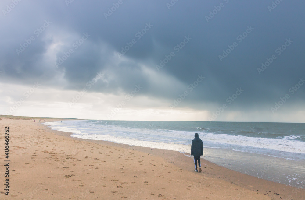 silhouette d'un adolescent seul sur une plage en hiver

