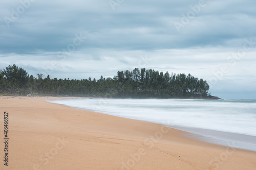 Dreamy tropical sea with wave foam at coastline on gloomy