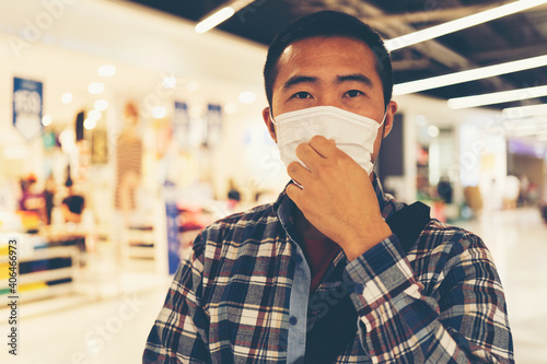 Portrait of young adult man putting on a covid virus protective mask