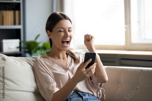 Close up overjoyed woman holding phone  screaming with joy  showing yes gesture  excited young female celebrating success  online lottery win  reading good news in email  using smartphone