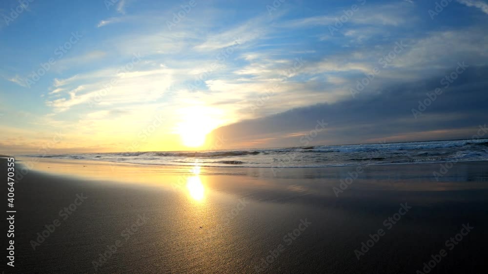 The sandy beaches of Monterey Bay at low tide. Sunset illuminating the wet sand. Salinas River State Beach, California (USA). Sea foam racing towards the camera. The sandy beaches of Monterey Bay at low tide. Sunset illuminating the wet sand. Salinas River State Beach, California (USA). Sea foam racing towards the camera.