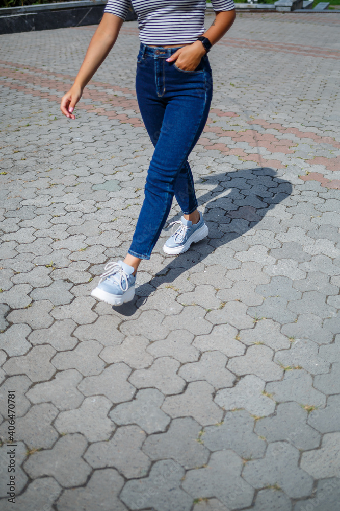 A beautiful girl with blond long hair of European appearance. Dressed in jeans and a T-shirt. Walk on a sunny day A beautiful girl with blond long hair of European appearance. Dressed in jeans and a T-shirt. Walk on a sunny day