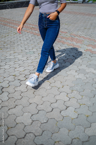 A beautiful girl with blond long hair of European appearance. Dressed in jeans and a T-shirt. Walk on a sunny day