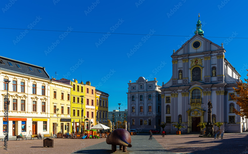View of Lower Square in Opava historic centre with Church of St. Adalbert and piece of modern art called Spy on sunny autumn day, Czech Republic