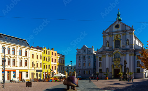 View of Lower Square in Opava historic centre with Church of St. Adalbert and piece of modern art called Spy on sunny autumn day, Czech Republic