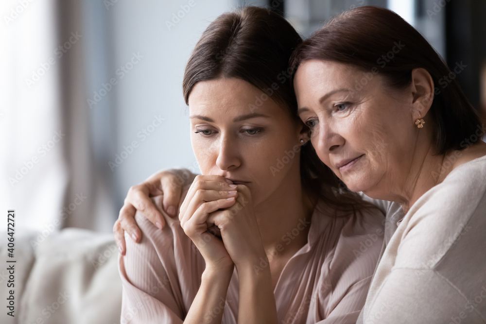 Naklejka premium Close up loving mature mother calming comforting frustrated grownup daughter, expressing empathy and support, helping to overcome problems, caring elderly mum hugging frustrated young woman