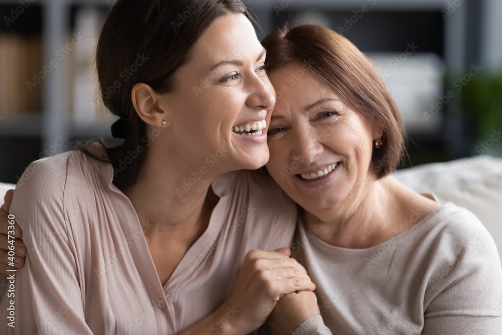 Close up head shot portrait smiling mature mother and grownup daughter cuddling, family enjoying tender moment, happy young woman with elderly mum hugging, spending leisure time together