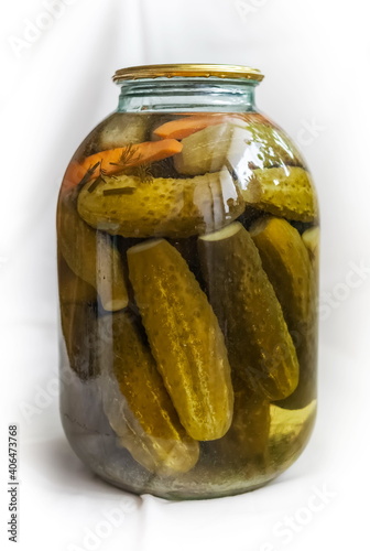 Pickles in a rolled-up metal lid three-liter glass jar on a white background