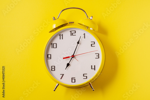 Yellow illuminating color Retro style alarm clock on yellow background.