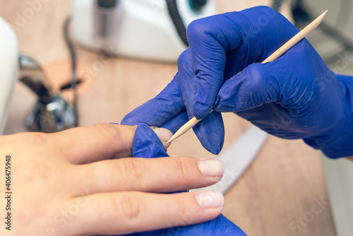 Manicurist doing a manicure in a nail salon using an orange stick