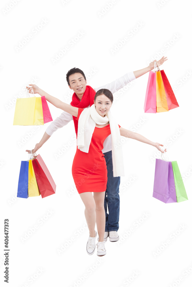 Portrait of young couple holding shopping bags,opening arms Portrait of young couple holding shopping bags,opening arms