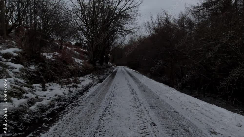 Driving snowy frozen rural country road in slippery winter conditions on frosty morning