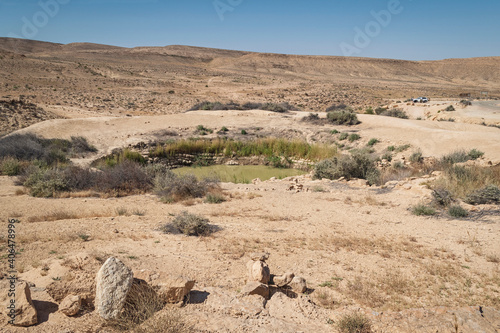 ancient iron age bor hemet cistern in the negev highlands near the west end of the makhtesh ramon crater in israel with tourists and clear sky in the background